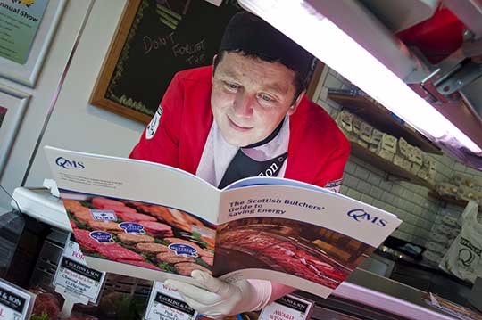 Butcher Stewart Collins reading up on energy saving measures in his shop in Glasgow.