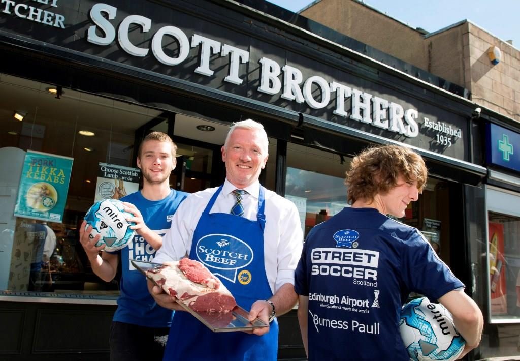 Scott Jarron owner of Scott Brothers butchers pictured with Team Scotland players Connor Henderson (left) and James Maich. Picture by Graeme Hart. Copyright: Perthshire Picture Agency.