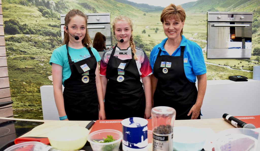 Young chefs Ela Preston and Mari Smith, from Ysgol y Gader, Dolgellau, join Elwen Roberts at the HCC stand at this year’s Royal Welsh Show.
