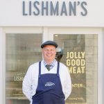 David Lishman's stands centrally in front of his shop, the 'Lishman's' sign clearly visibly above him.